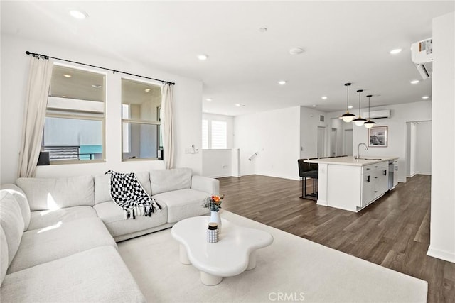 living room with a wall mounted air conditioner, dark hardwood / wood-style flooring, and sink