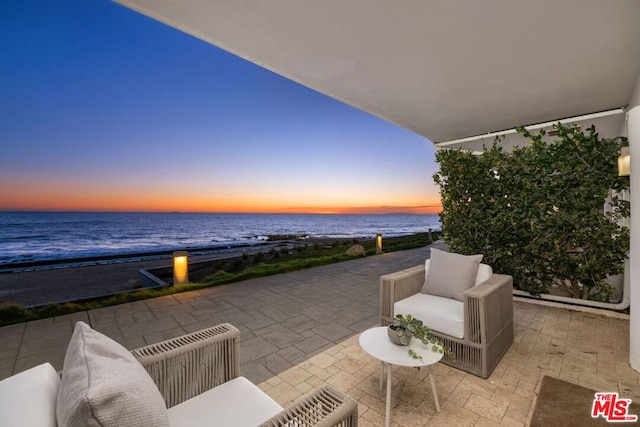 patio terrace at dusk with a view of the beach and a water view