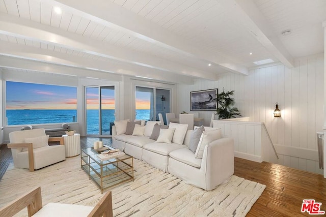 living room featuring beamed ceiling, light wood-type flooring, and a water view