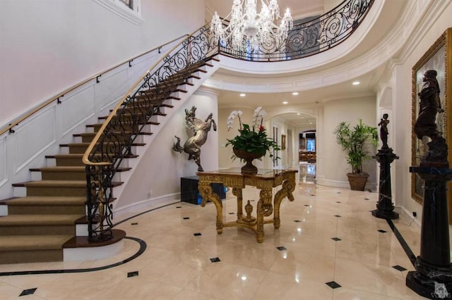 entryway featuring a towering ceiling, crown molding, and an inviting chandelier