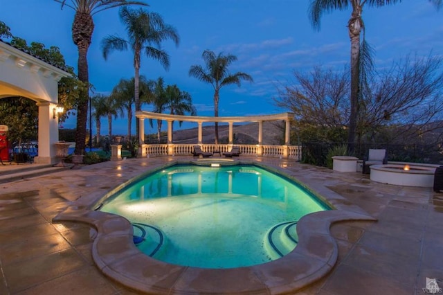 pool at dusk featuring an in ground hot tub and a patio area