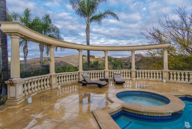 view of pool with an in ground hot tub, a mountain view, and a patio area