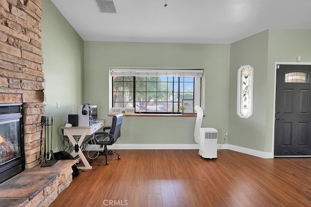 unfurnished office featuring hardwood / wood-style flooring and a fireplace