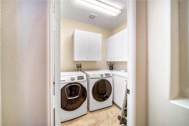 laundry room featuring cabinets, light tile patterned floors, and washing machine and dryer