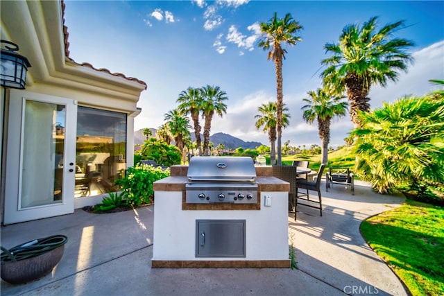 view of patio with a mountain view, grilling area, and exterior kitchen