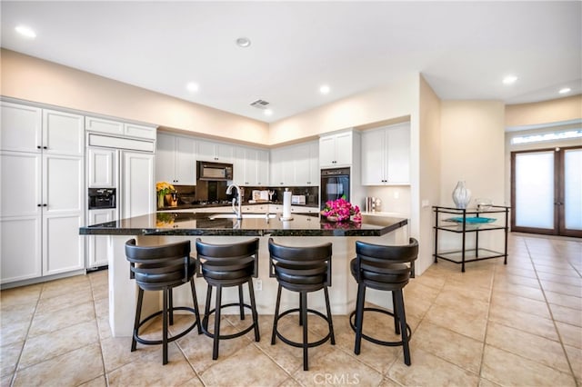 kitchen featuring a kitchen breakfast bar, white cabinetry, a center island with sink, and light tile patterned floors