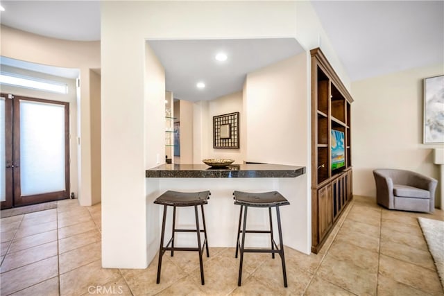 kitchen with kitchen peninsula, a breakfast bar, and light tile patterned flooring