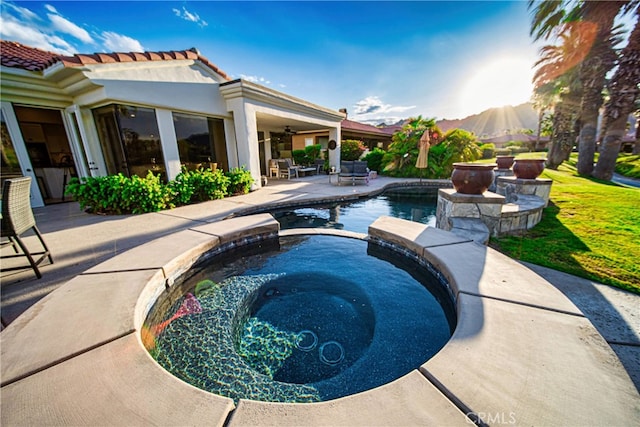 view of pool with an in ground hot tub, a mountain view, a patio, and ceiling fan