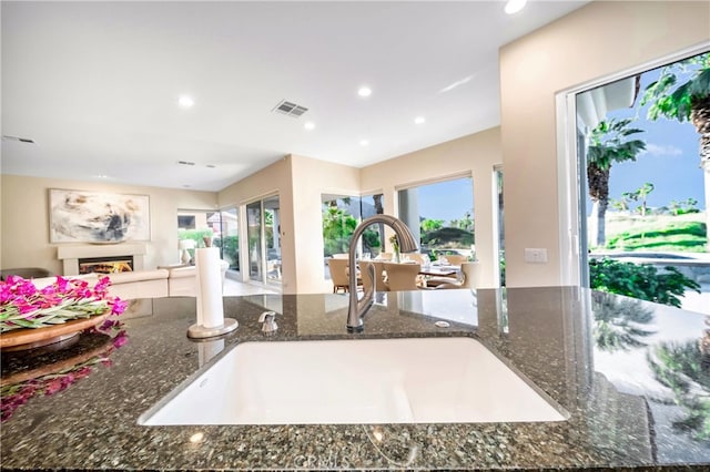 kitchen with a wealth of natural light, dark stone counters, and sink