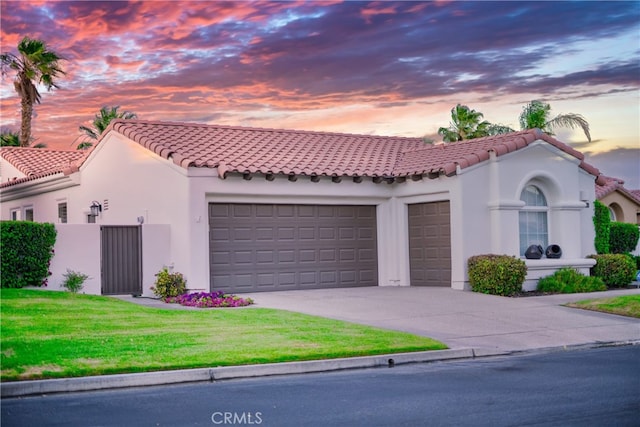 mediterranean / spanish-style home featuring a garage and a yard