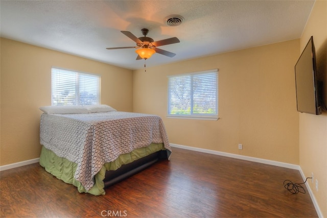 bedroom with a textured ceiling, dark hardwood / wood-style floors, and ceiling fan