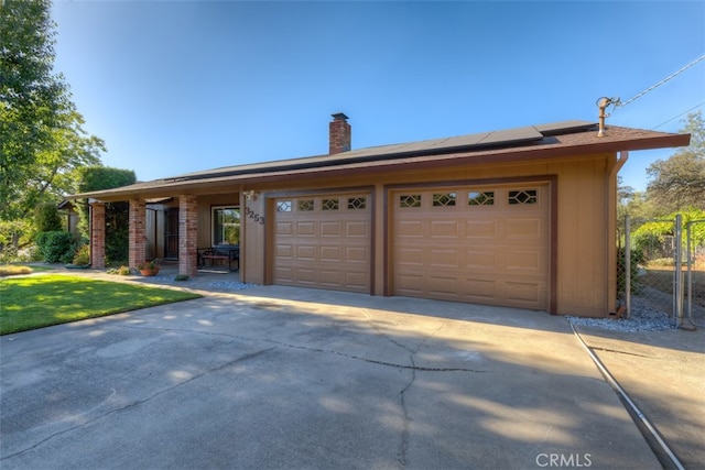 ranch-style house featuring a garage, solar panels, and a front yard