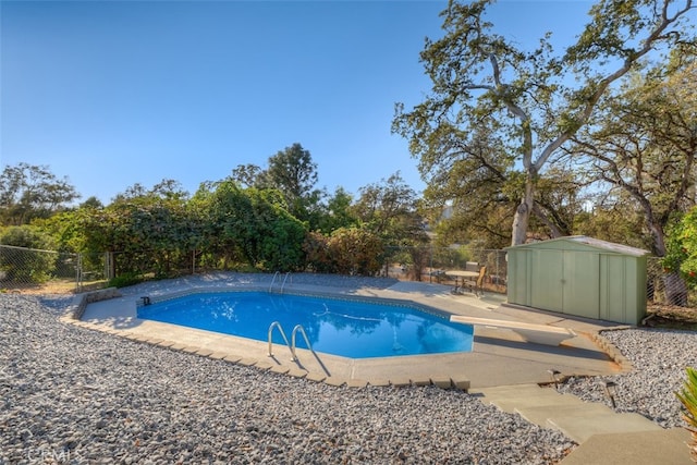 view of pool with a patio, a diving board, and a shed