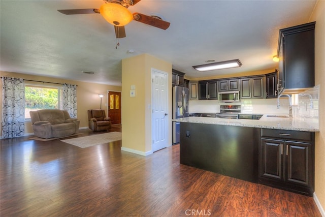 kitchen with light stone counters, dark hardwood / wood-style floors, sink, stainless steel appliances, and dark brown cabinetry