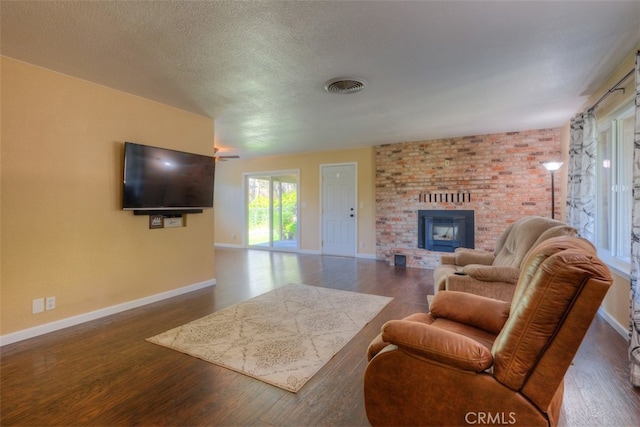 living room featuring a brick fireplace, a textured ceiling, and dark hardwood / wood-style floors