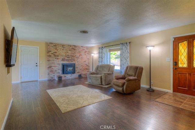 living room featuring a textured ceiling, dark hardwood / wood-style flooring, and a wood stove