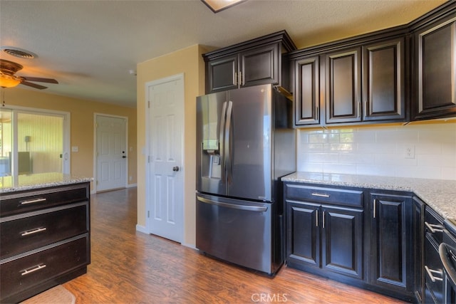 kitchen with stainless steel refrigerator with ice dispenser, hardwood / wood-style floors, ceiling fan, and light stone counters