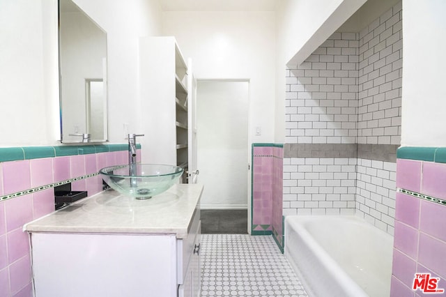 bathroom with tile walls, a tub to relax in, and vanity