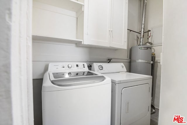 washroom featuring washing machine and clothes dryer, cabinets, and gas water heater