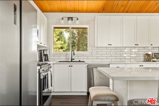 kitchen with white cabinetry, appliances with stainless steel finishes, tasteful backsplash, and a breakfast bar area