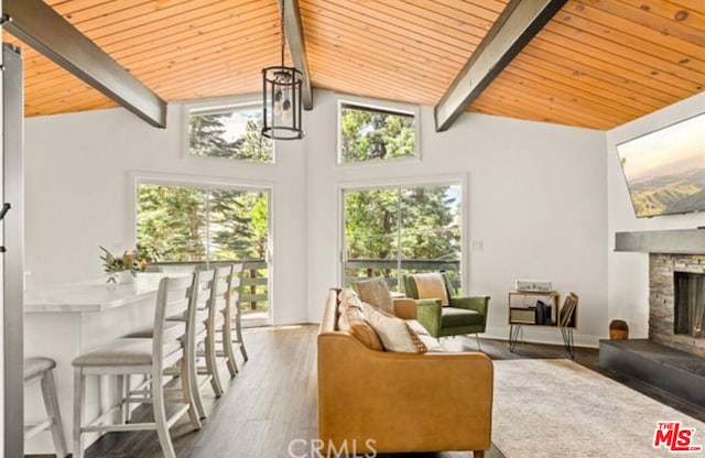 sunroom / solarium featuring a stone fireplace, vaulted ceiling with beams, and wooden ceiling