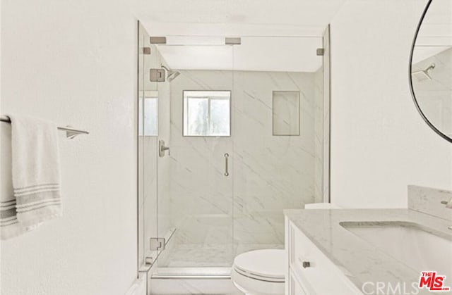 bathroom featuring vanity, toilet, and a shower with door