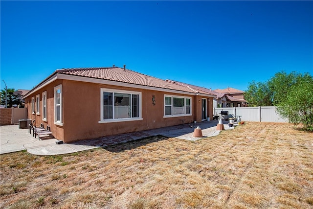 rear view of house featuring a lawn and a patio