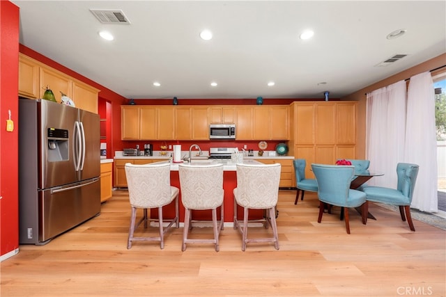 kitchen featuring an island with sink, sink, light hardwood / wood-style flooring, and stainless steel appliances