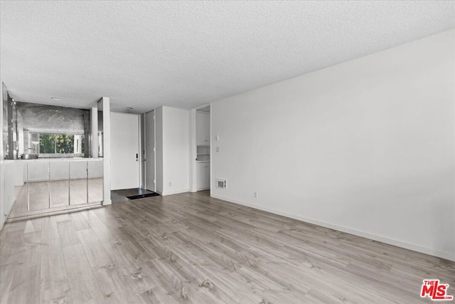 unfurnished living room featuring light wood-type flooring and a textured ceiling