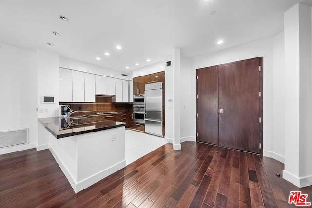 kitchen with sink, light hardwood / wood-style flooring, white cabinetry, kitchen peninsula, and stainless steel appliances