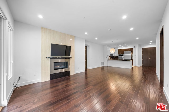 unfurnished living room with dark hardwood / wood-style flooring and a large fireplace