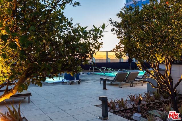 patio terrace at dusk with a fenced in pool