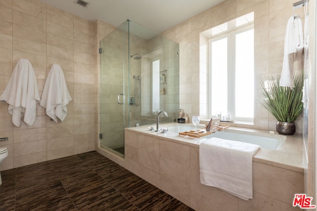 bathroom with shower with separate bathtub, tile walls, and toilet