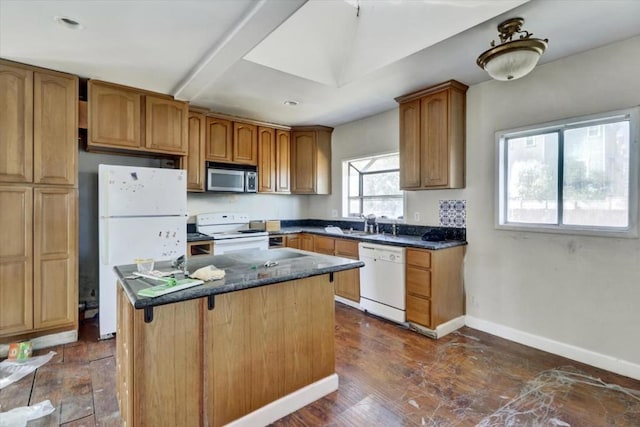 kitchen featuring a center island, sink, white appliances, dark hardwood / wood-style flooring, and dark stone countertops