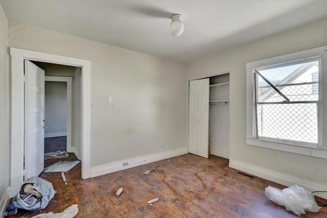 unfurnished bedroom with a closet and dark hardwood / wood-style flooring