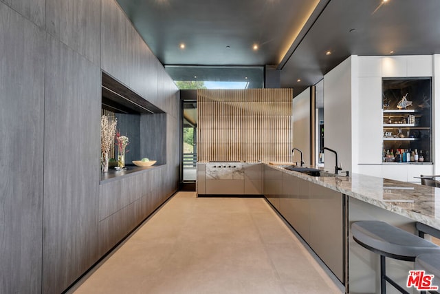 kitchen with light stone countertops, a breakfast bar, and sink