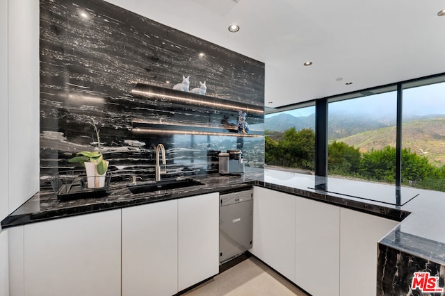 bar featuring white cabinets, dishwasher, dark stone countertops, and sink