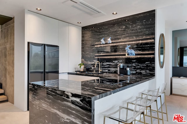 kitchen with dark stone counters, sink, black electric cooktop, tasteful backsplash, and white cabinetry