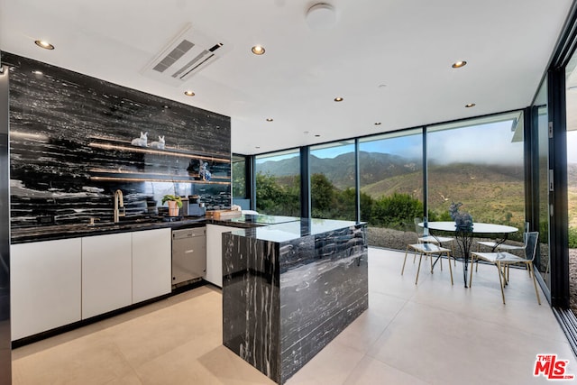 kitchen featuring expansive windows, dark stone counters, a mountain view, dishwasher, and white cabinets