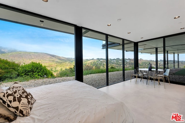 bedroom featuring multiple windows, a mountain view, and floor to ceiling windows