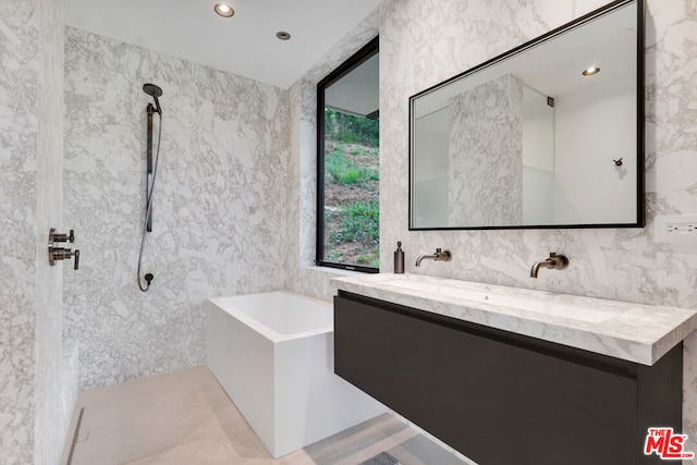 bathroom featuring plus walk in shower, vanity, and tile walls