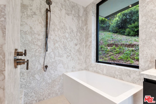 bathroom with tile patterned flooring, a bath, vanity, and tile walls