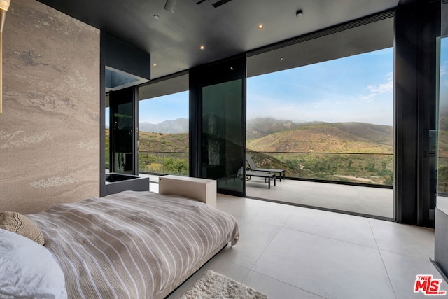 bedroom featuring a mountain view and expansive windows