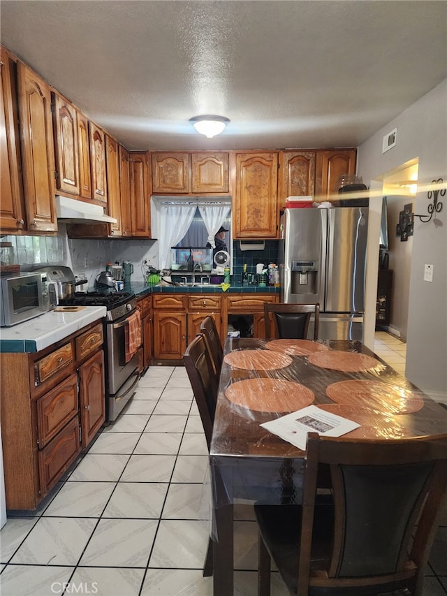 kitchen with appliances with stainless steel finishes, backsplash, a textured ceiling, and sink