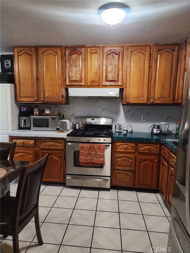 kitchen with appliances with stainless steel finishes, backsplash, and a textured ceiling