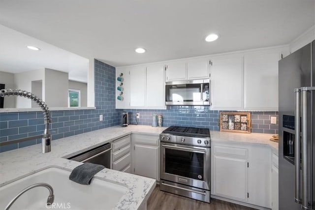 kitchen featuring light stone countertops, appliances with stainless steel finishes, dark hardwood / wood-style flooring, tasteful backsplash, and white cabinetry