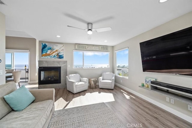 living room featuring ceiling fan, light wood-type flooring, and a fireplace