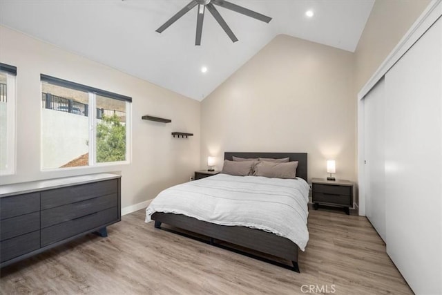 bedroom featuring ceiling fan, a closet, high vaulted ceiling, and light hardwood / wood-style floors