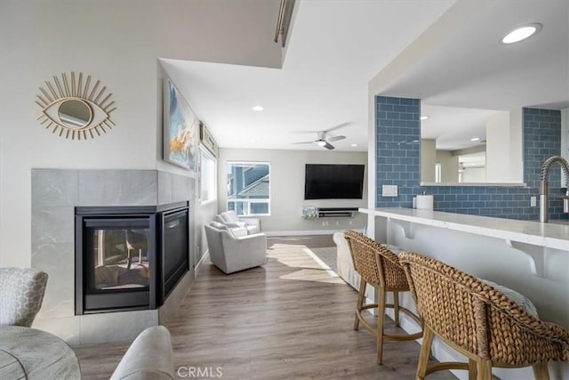 living room featuring ceiling fan, light hardwood / wood-style floors, and a fireplace