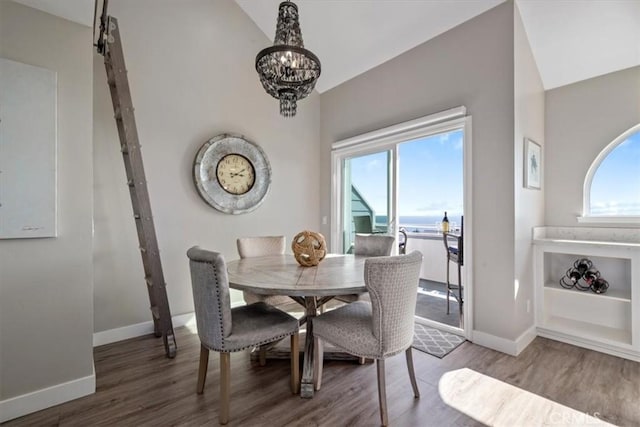 dining room with hardwood / wood-style floors, a barn door, an inviting chandelier, and lofted ceiling